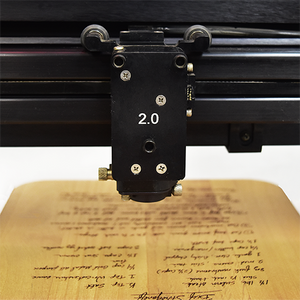 A laser machine personalizing a wood cutting board with a handwritten recipe